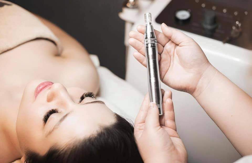 Microneedlingbehandeling in de salon: de pen wordt boven het gezicht van een cliënt klaargehouden